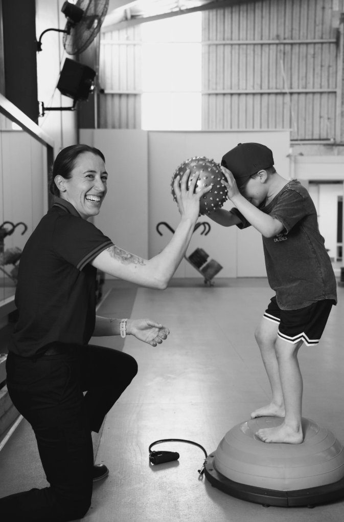 Grace Buchan working with a young patient on a balance trainer in the clinic