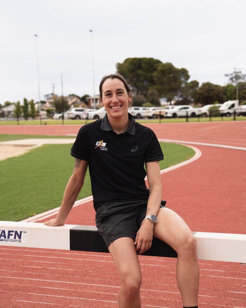 Grace Buchan sitting on a hurdle at the Griffith athletics track